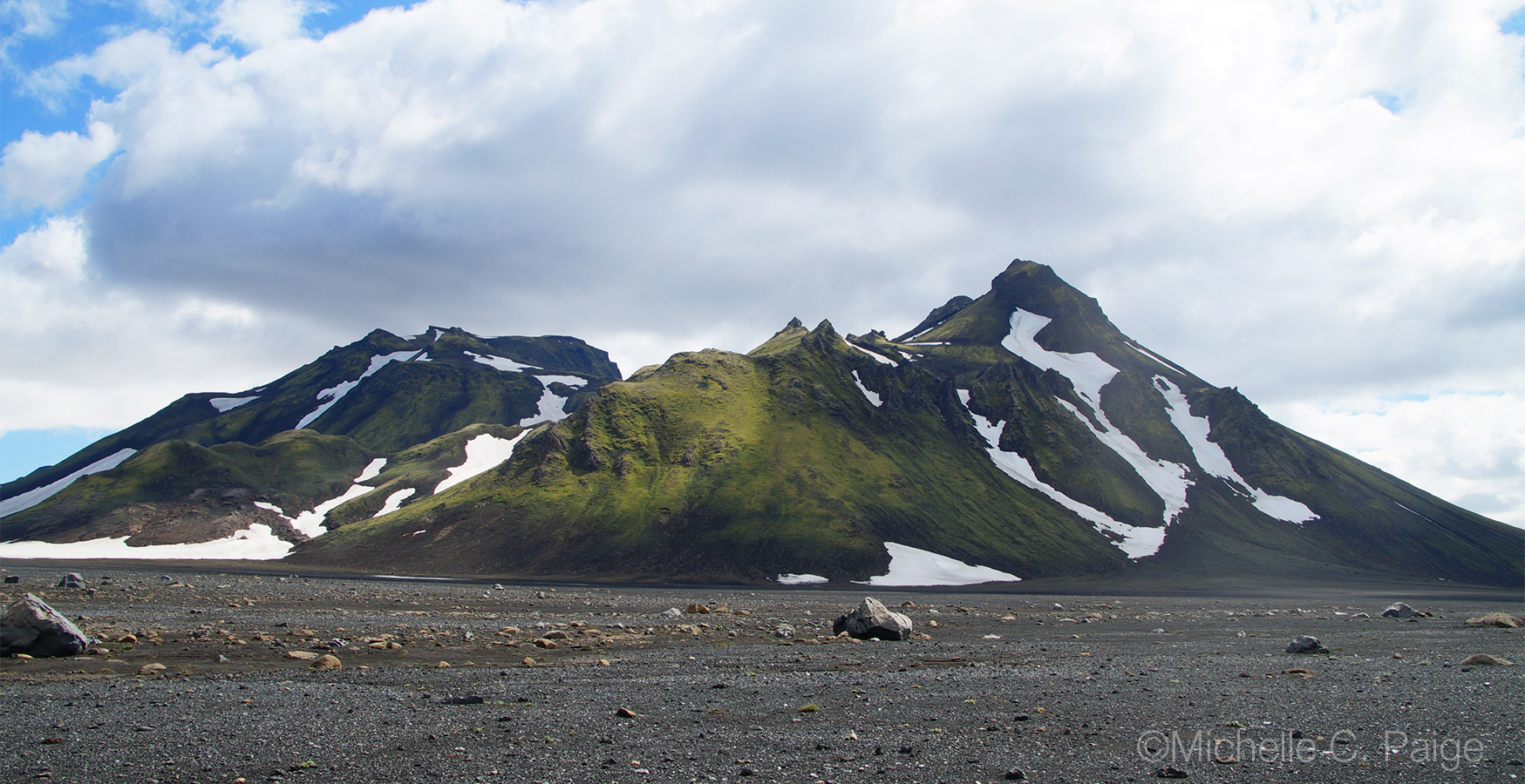 Green mountain on the Laugavegur trail behind black sand desert
